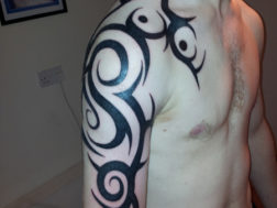 Художественная татуировка в стиле trible на мужском плече