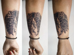 Татуировка на предплечье в виде крыльев с инициалами дететей